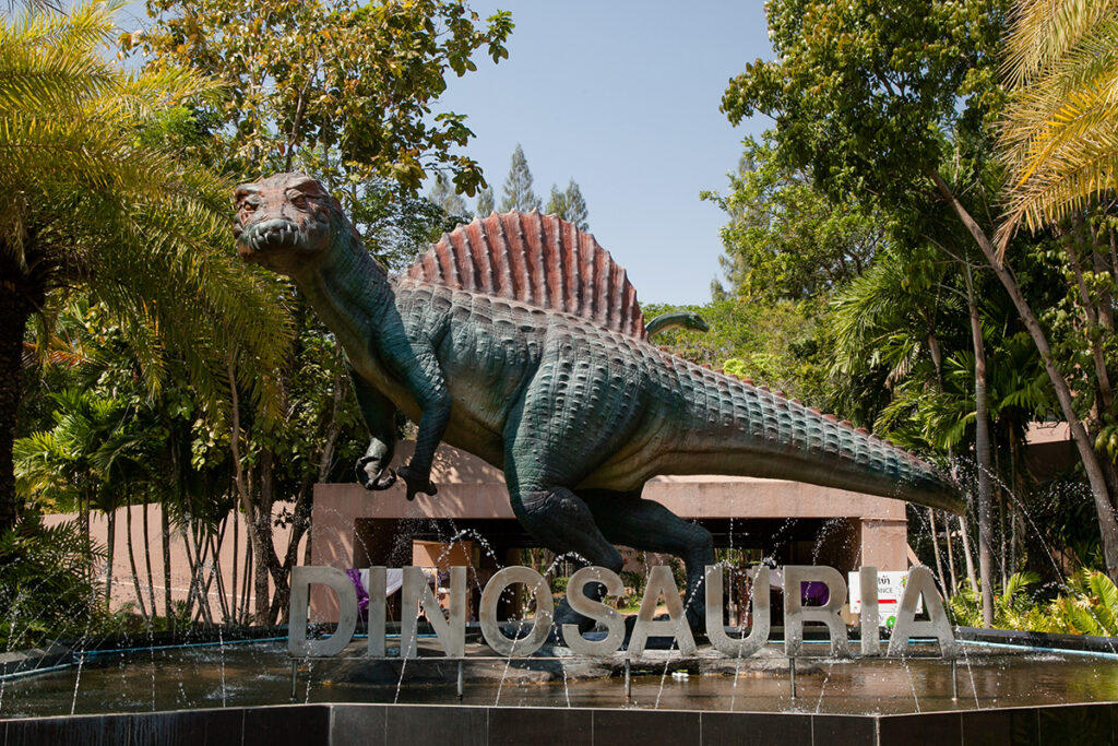 Colorful statue of Siamosaurus suteethorni with sail-like spine, displayed in a fountain at the Sirindhorn Dinosaur Museum.