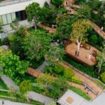 Aerial view of lush Roof Park at Central Park Bangkok with wooden walkways.