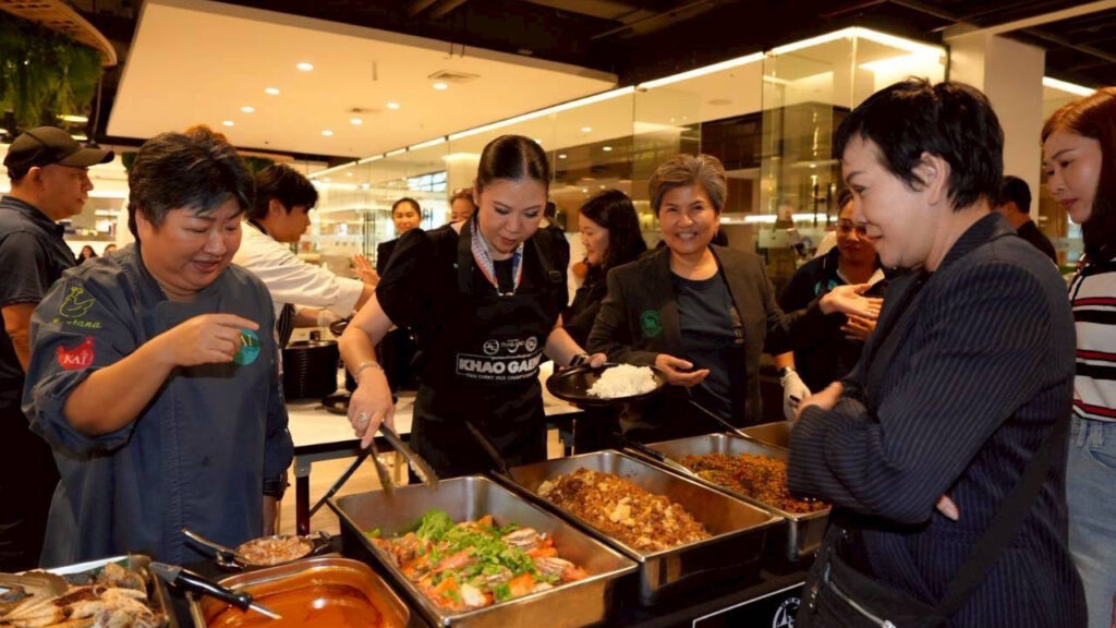 Serving line at Khao Gaeng event – TAT Governor and chefs serving curry rice dishes to guests.