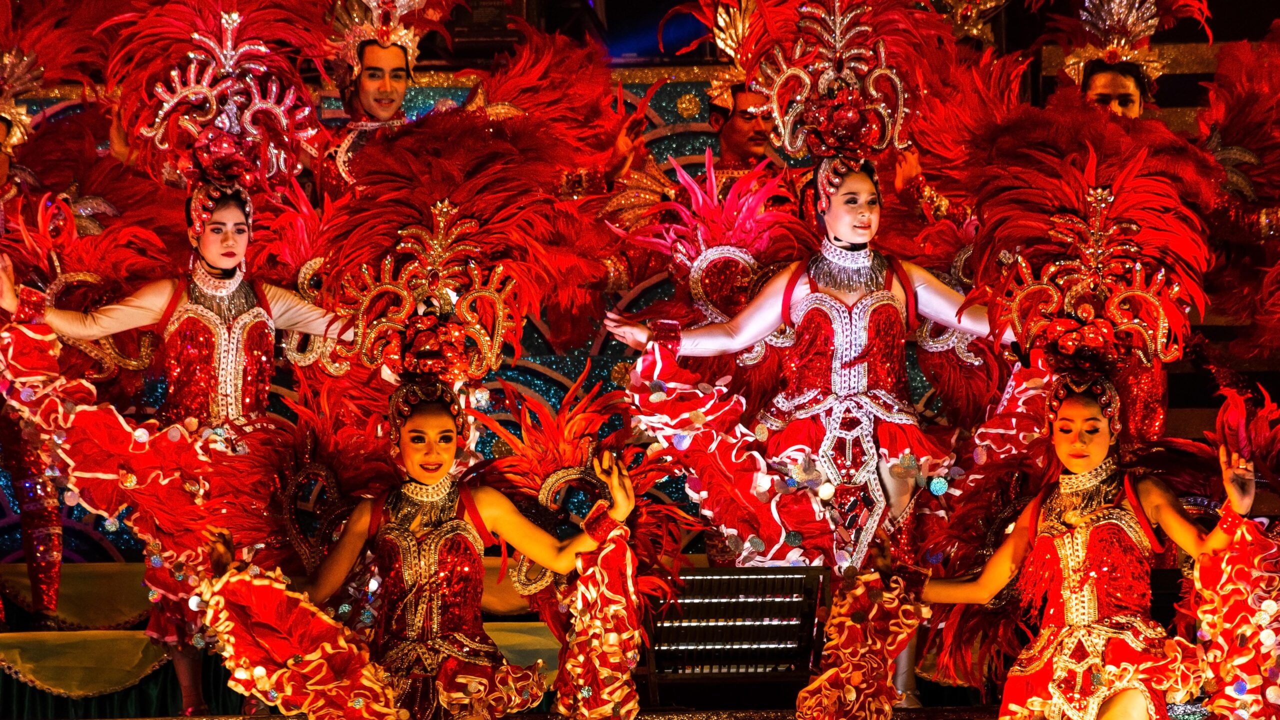 Molam performers in red costumes with feathered headdresses during vibrant show at Molam Festival 2025