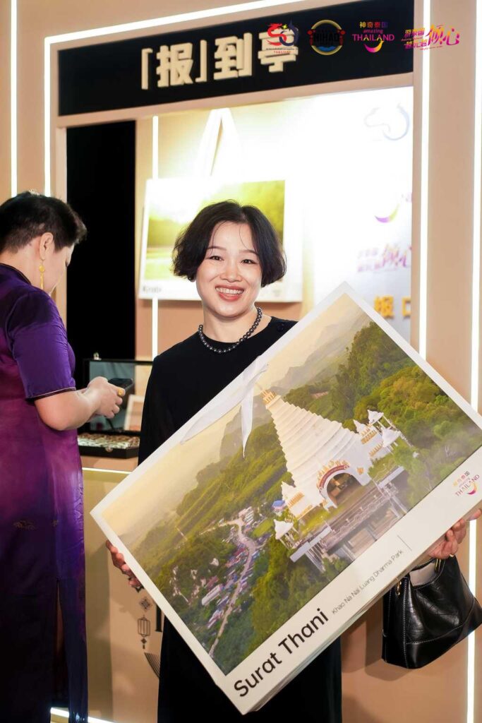 Chinese guest holding Surat Thani travel poster at Nihao Month event.