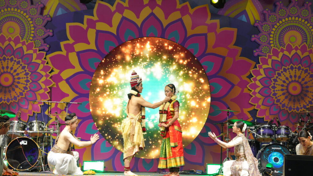 Performers reenact the divine union of Rama and Sita in a Thai-Indian Ramayana dance performance under vibrant stage lighting.