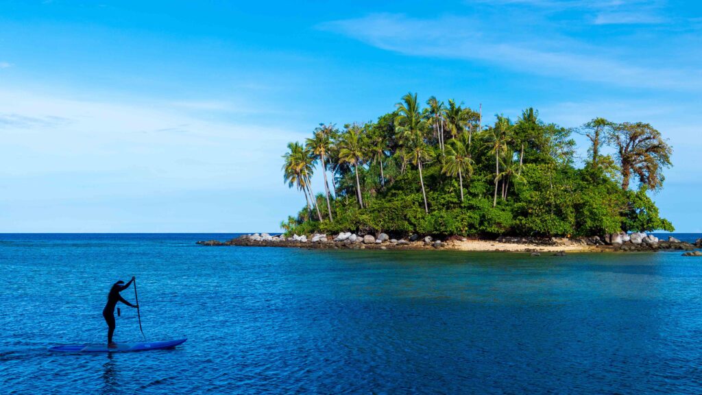 Paddleboarder gliding over turquoise waters near Ko Pling Island in Sirinat National Park, Phuket.