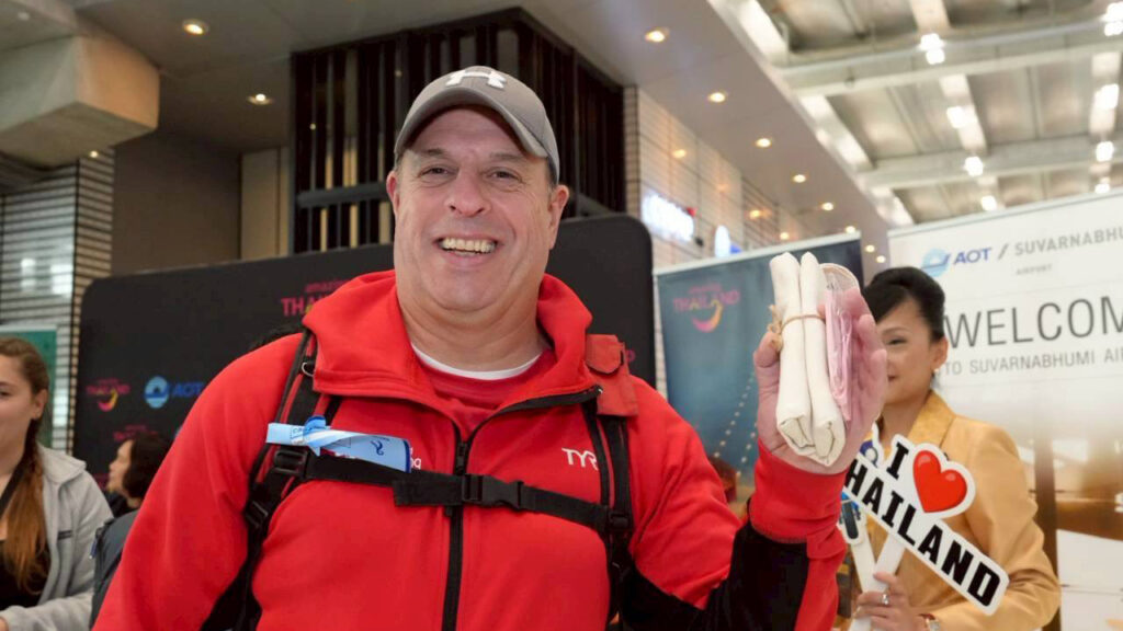 Tourist smiles while holding a welcome gift from TAT after arriving on Norse Atlantic Airways’ inaugural London–Bangkok service.