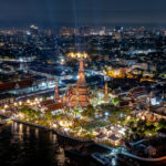 Aerial view of Wat Arun and the Chao Phraya River beautifully lit during a nighttime festival in Bangkok.