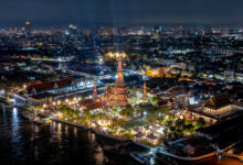 Aerial view of Wat Arun and the Chao Phraya River beautifully lit during a nighttime festival in Bangkok.