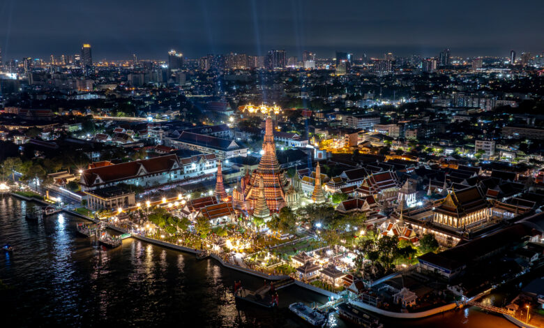Aerial view of Wat Arun and the Chao Phraya River beautifully lit during a nighttime festival in Bangkok.