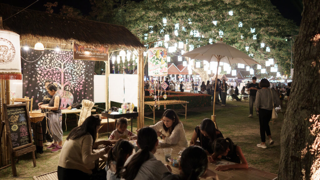 Local artisans demonstrate traditional Thai crafts under lanterns at the festive marketplace.