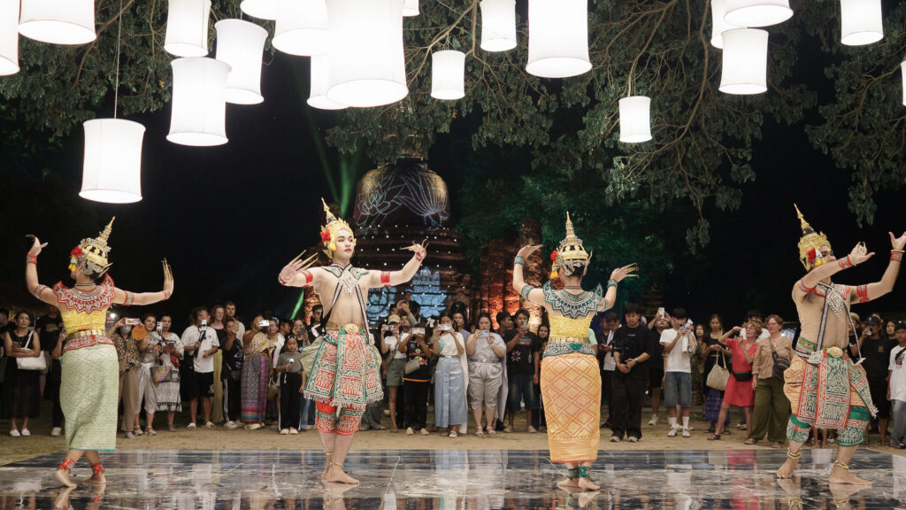 Traditional masked dancers perform Thai classical dance under lanterns during the festival.