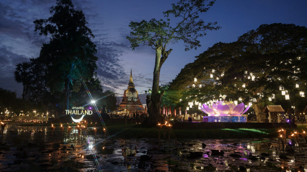 A large illuminated lotus installation and floating candles enhance the serene night atmosphere at Sukhothai.