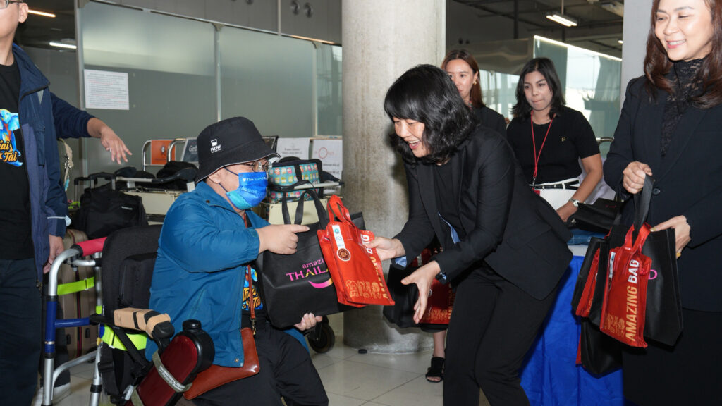 A TAT representative warmly presents welcome gifts to a Taiwanese traveller using a wheelchair during the arrival ceremony at Suvarnabhumi Airport.