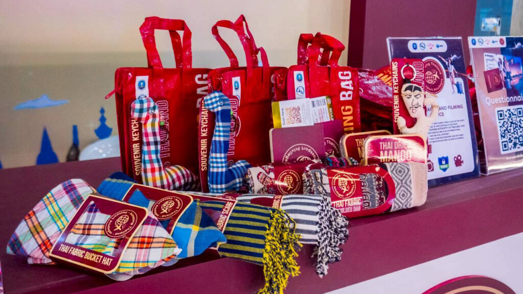 Display of red “Amazing Bag” souvenirs featuring Thai crafts, textiles, and keychains representing the 5 Must Do in Thailand experiences.