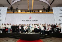 A large group of chefs and representatives stand on stage during the MICHELIN Guide Ceremony Thailand 2026, celebrating new award recipients.