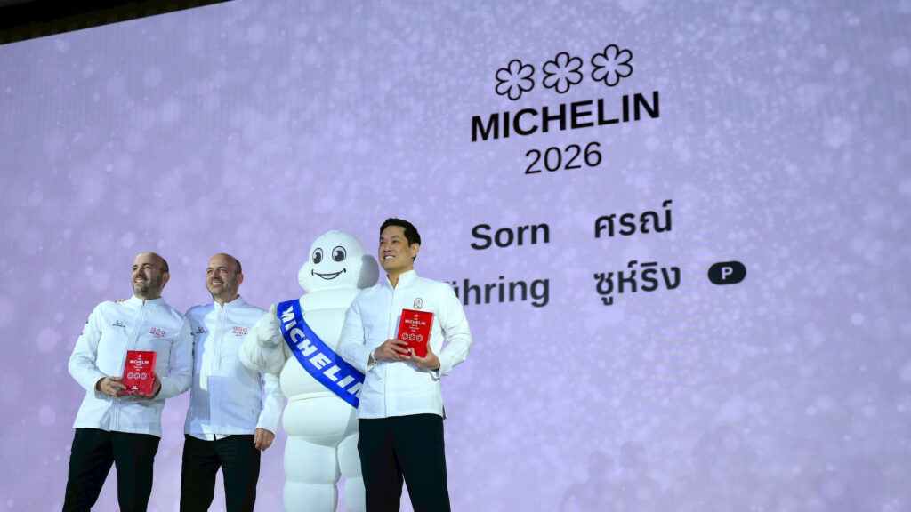 Chefs receiving Three MICHELIN Star recognition stand on stage with the Michelin Man during the MICHELIN Guide Thailand 2026 ceremony, holding their red plaques.