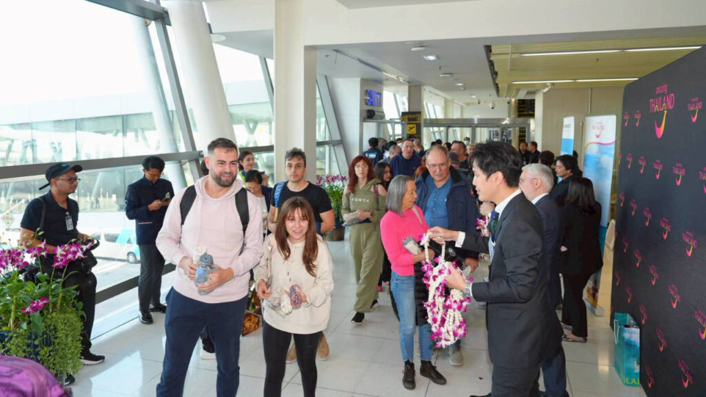 Passengers from the inaugural Air France Paris–Phuket flight walking through the arrival area as TAT staff present welcome garlands.