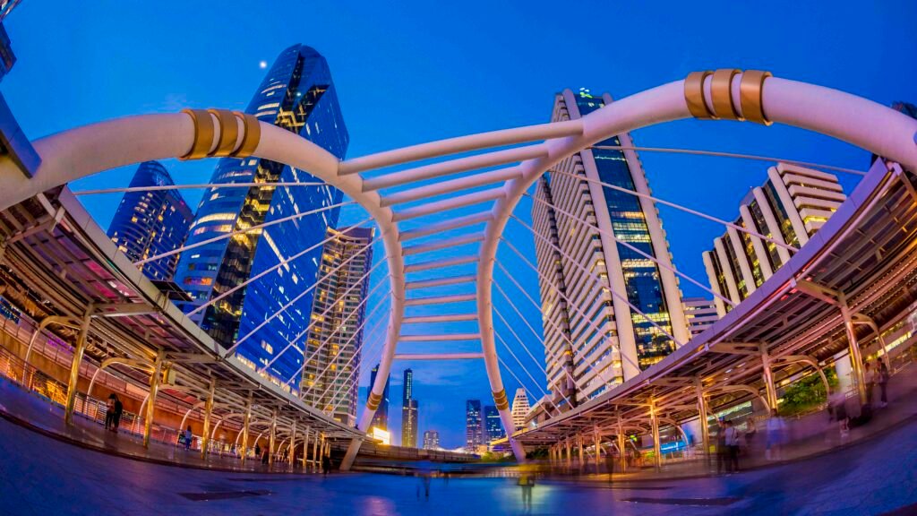 Chong Nonsi Skywalk framed by modern skyscrapers in Bangkok’s central business district during early evening.