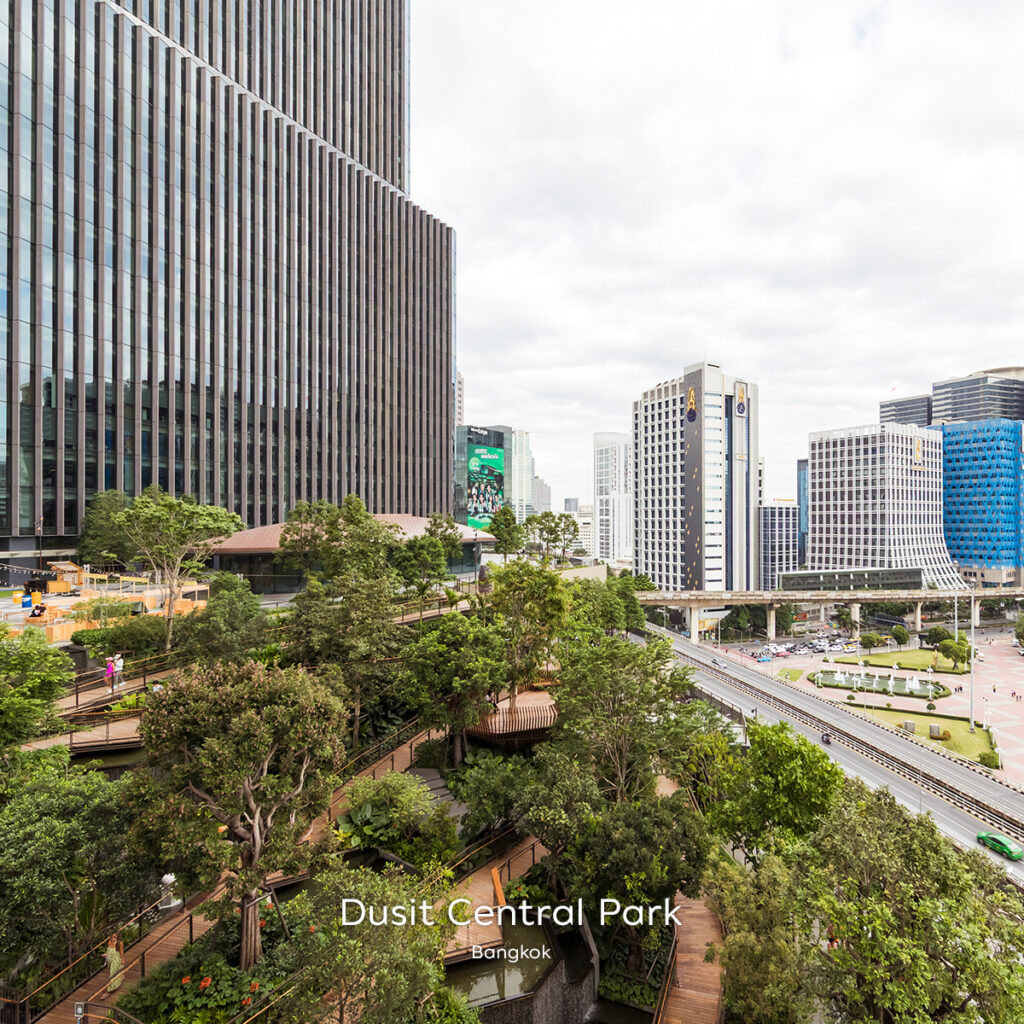 Tree-filled elevated park at Dusit Central Park with wooden paths framed by Bangkok’s modern high-rise skyline.