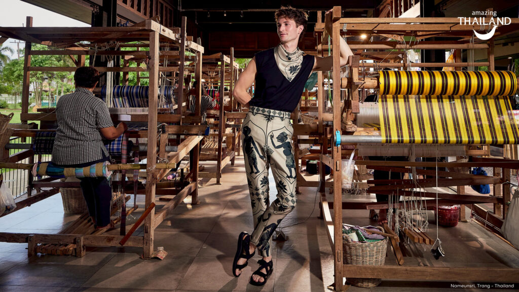 British singer-songwriter Henry Moodie poses inside a traditional weaving workshop, surrounded by wooden looms and handwoven textiles, highlighting local craftsmanship and cultural heritage.