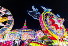 Illuminated star floats parade past the Cathedral of St Michael the Archangel during the Sakon Nakhon Christmas Star Parade, with angel motifs and vibrant lights lighting up the night sky.