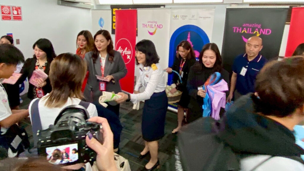 TAT and airline representatives hand out welcome kits to youth athletes during the Sendai–Bangkok inaugural flight reception.