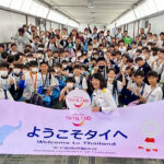 A large group of youth football players from Japan hold a “Welcome to Thailand” banner as TAT staff greet them on arrival in Bangkok.