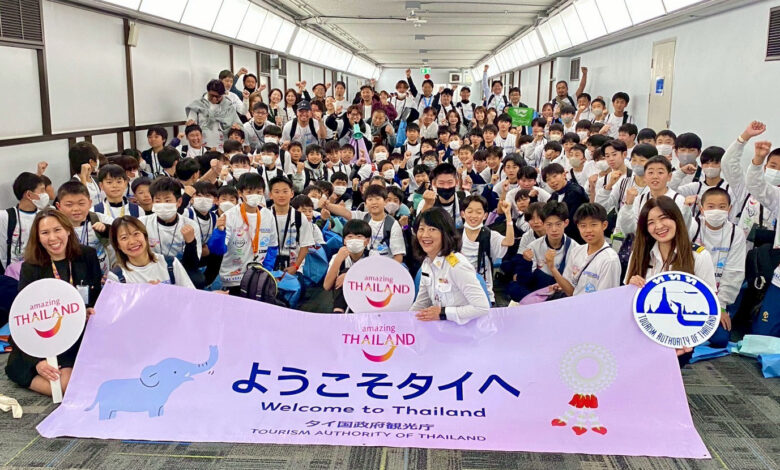A large group of youth football players from Japan hold a “Welcome to Thailand” banner as TAT staff greet them on arrival in Bangkok.