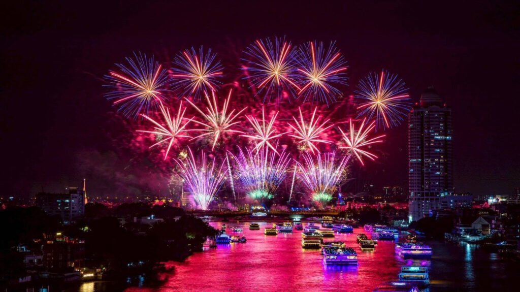 Fireworks illuminate the Chao Phraya River during the closing night of Vijit Chao Phraya 2025, with illuminated cruise boats and Bangkok’s skyline reflecting vibrant colours along the river.