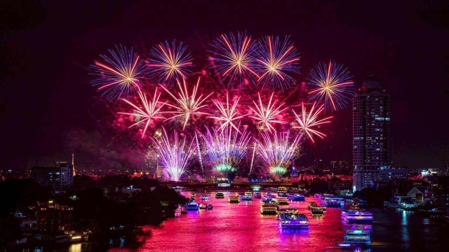 Fireworks illuminate the Chao Phraya River during the closing night of Vijit Chao Phraya 2025, with illuminated cruise boats and Bangkok’s skyline reflecting vibrant colours along the river.