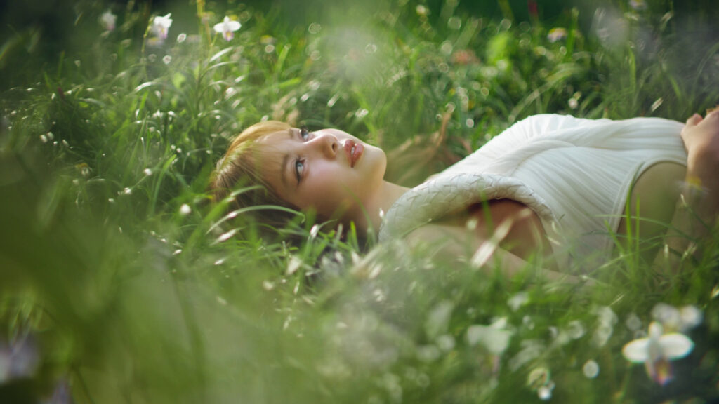 Lalisa “LISA” Manobal resting in a sunlit meadow in a white outfit