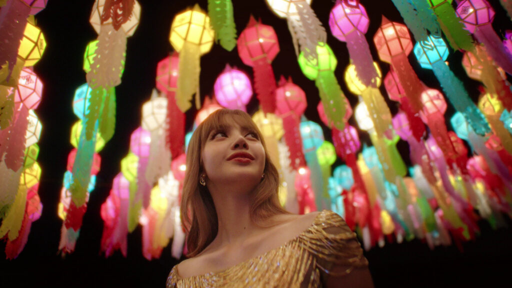Lalisa “LISA” Manobal in a gold dress beneath colourful hanging lanterns at night