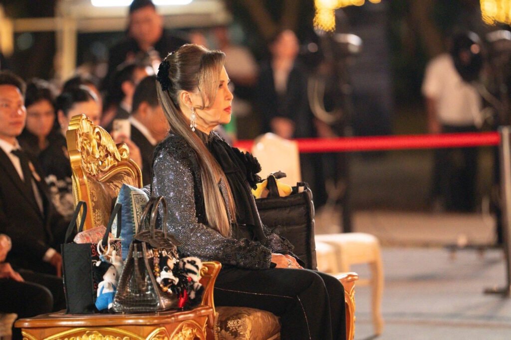 HRH Princess Ubolratana is seated on an ornate chair during the opening ceremony of The Night by Amazing Thailand at Lumpini Park, with officials and attendees in formal attire gathered in the evening setting.