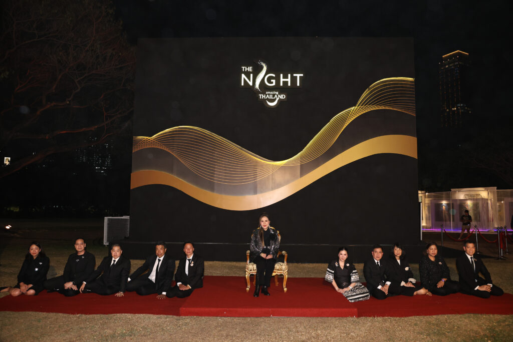 A wide ceremonial view shows HRH Princess Ubolratana seated at centre stage, flanked by officials and event representatives, with The Night by Amazing Thailand stage backdrop illuminated behind them.