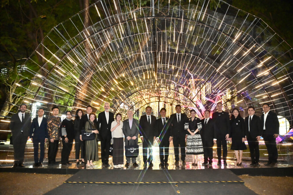 Guests and officials stand beneath a tunnel of illuminated light installations at Lumpini Park, showcasing the night-time visual design of The Night by Amazing Thailand.