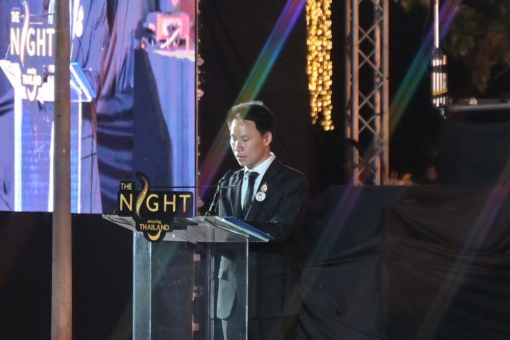 Mr. Artthakorn Sirilatthayakorn, Minister of Tourism and Sports delivers opening remarks at the podium on the main stage of The Night by Amazing Thailand, with stage lighting and event branding visible.