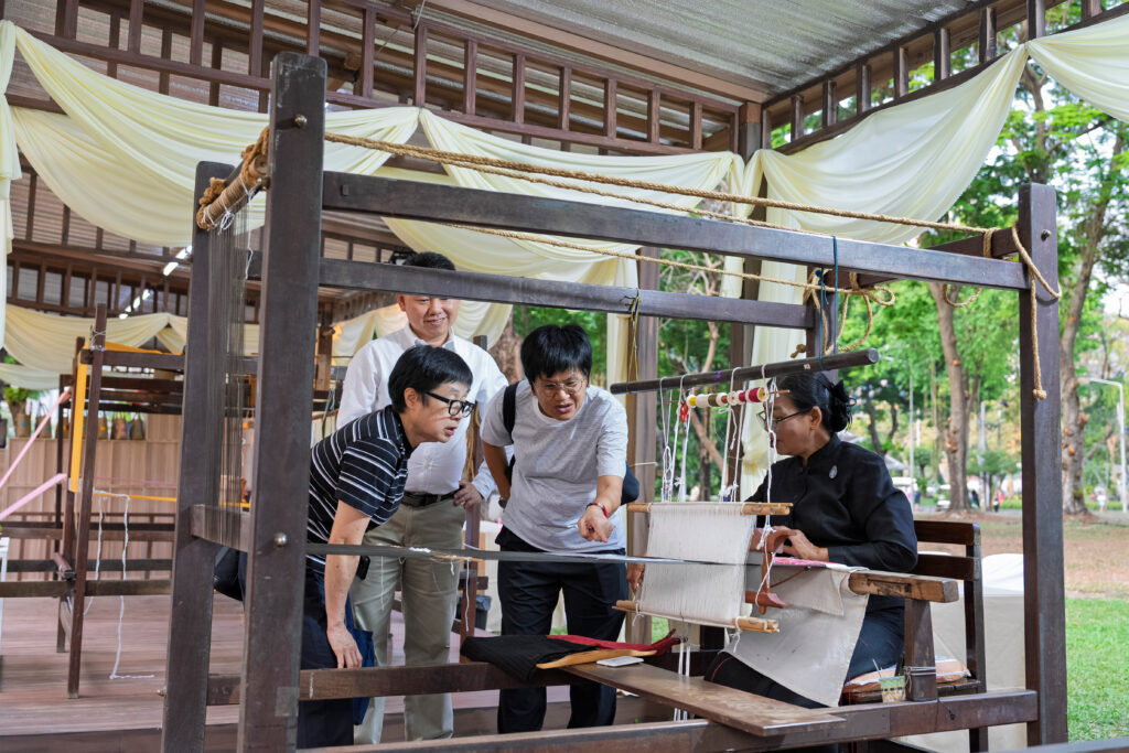 Visitors observe and engage with a live silk weaving demonstration by a master artisan from the SUPPORT Foundation, highlighting traditional craftsmanship showcased at the festival.