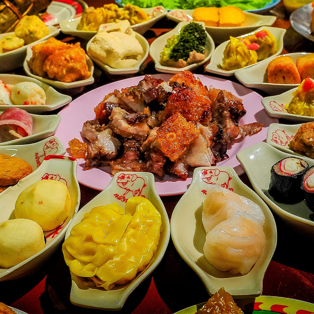 Traditional Trang breakfast with dim sum and crispy pork, showcasing Southern Thailand’s Chinese culinary heritage.