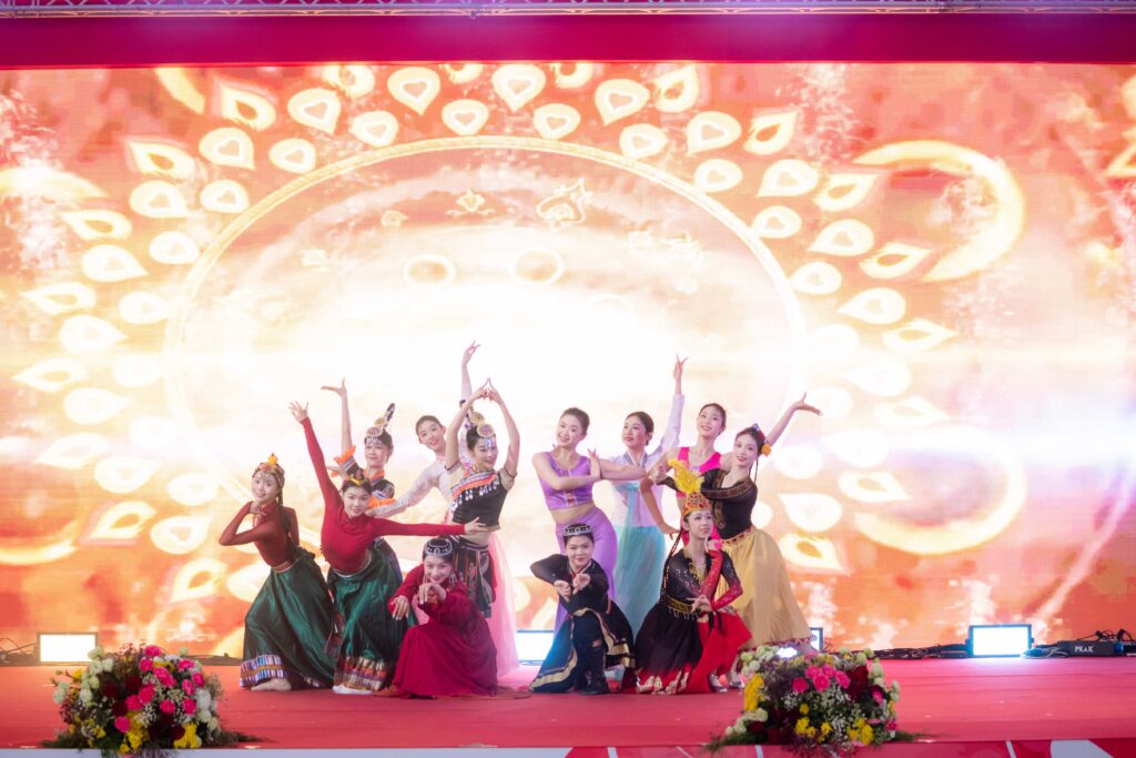 Cultural dance troupe posing on stage against a festive Chinese New Year backdrop in Bangkok.