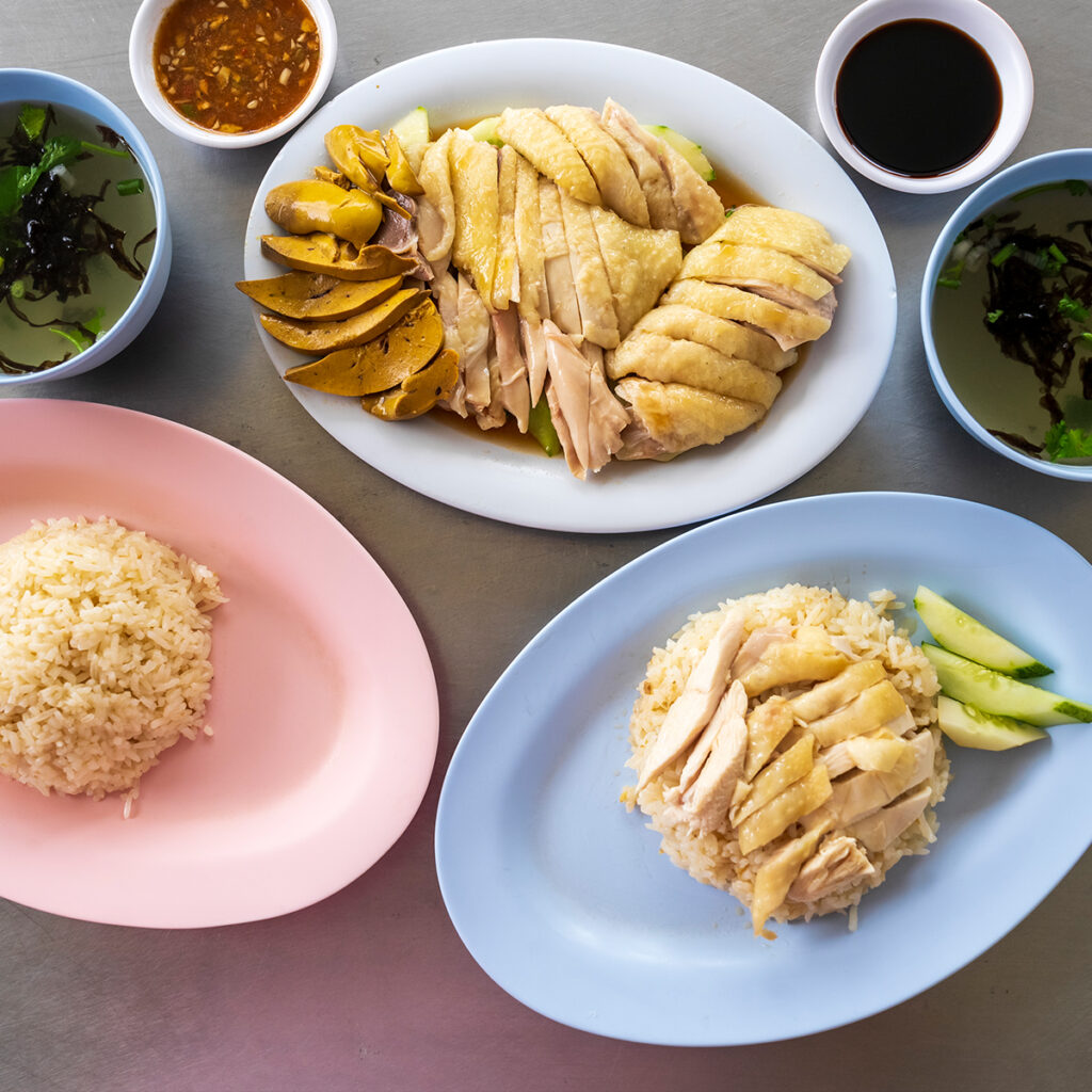 Khao Man Gai with poached chicken and garlic rice served with spicy fermented soybean sauce, reflecting Chinese roots in Thai cuisine.