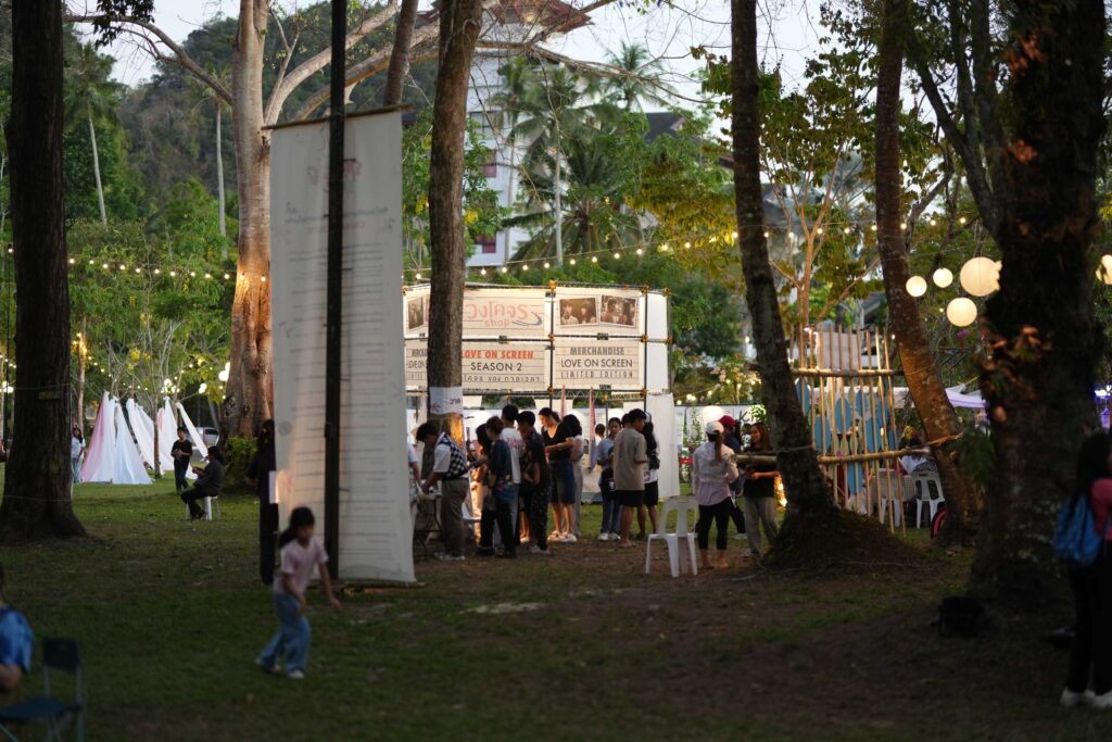 Visitors gather at open-air Love on Screen Film Festival in Krabi with illuminated stalls and outdoor cinema setting.
