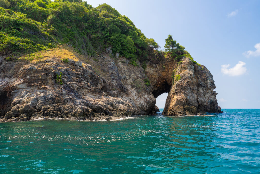 Natural rock arch at Ko Thalu in Rayong rising from clear turquoise waters, highlighting the calm and freedom of Thailand’s eastern seascape.