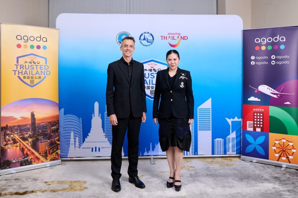 Senior representatives from the Tourism Authority of Thailand and Agoda pose together in front of Trusted Thailand branding and Amazing Thailand visuals following discussions on the initiative.