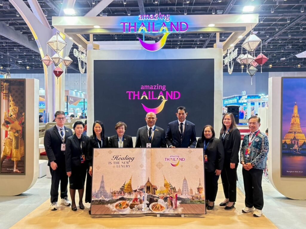 Group photo at the Thailand pavilion during Outbound Travel Mart 2026 in Mumbai, showing Tourism Authority of Thailand executives and staff beneath the Amazing Thailand branding and the Healing is the New Luxury campaign backdrop.