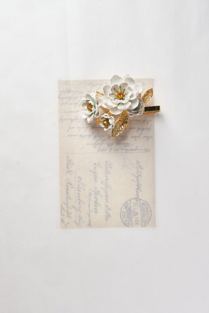 SARRAN The Ambassador Collection floral brooch featuring Dok Rak and jasmine details in gold and porcelain tones.