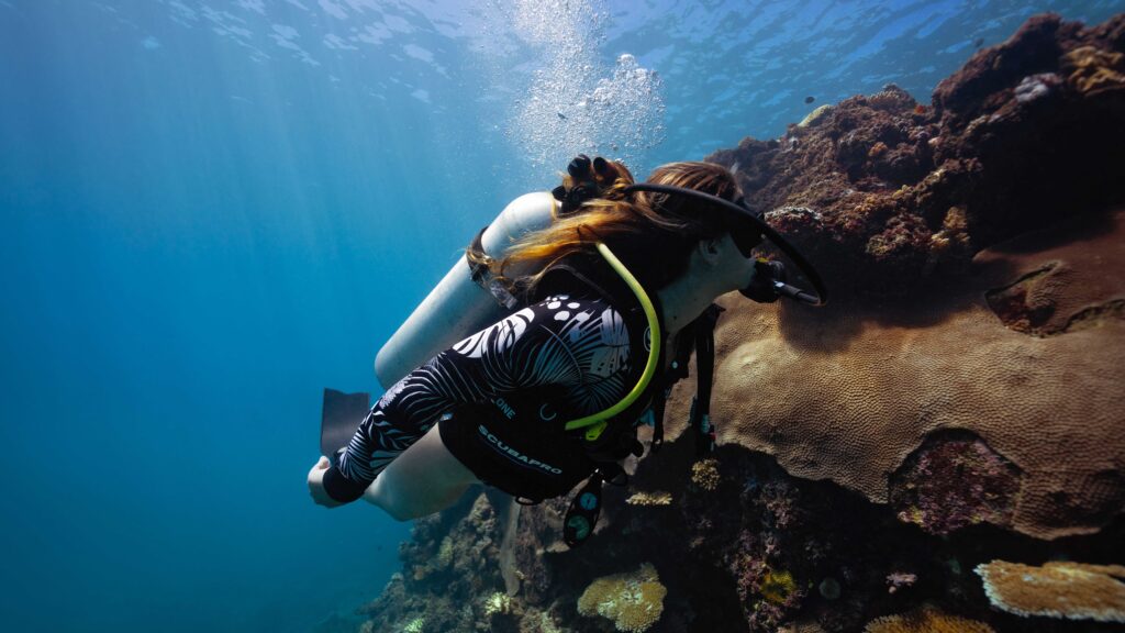 Diver observes coral reef ecosystems in Thailand as part of conservation-focused scuba diving experiences