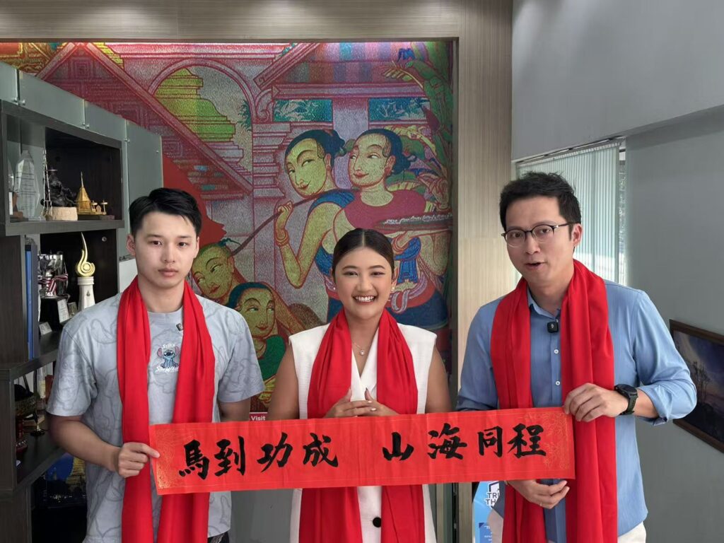 TAT and Chinese TV hosts hold red Chinese New Year banner during ‘Travel Across Mountains and Seas’ filming in northern Thailand.