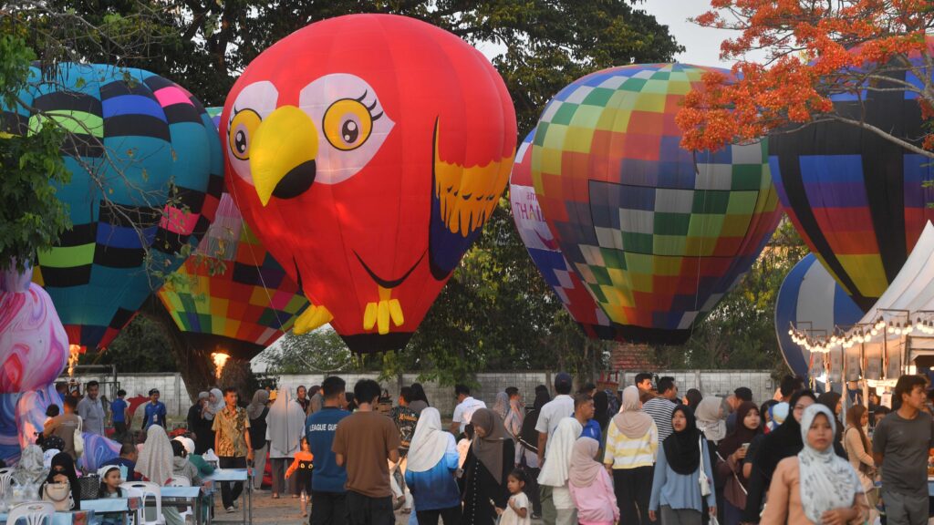 Visitors explore Smile @Pattani festival with giant hot air balloons, local food stalls, and family-friendly activities in Pattani