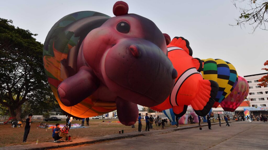 Giant animal-shaped hot air balloons being prepared at Smile @Pattani festival with visitors and staff on site