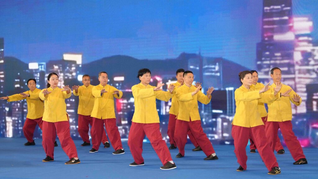 Tai Chi performers in yellow and red outfits demonstrate traditional movements on stage in Bangkok.