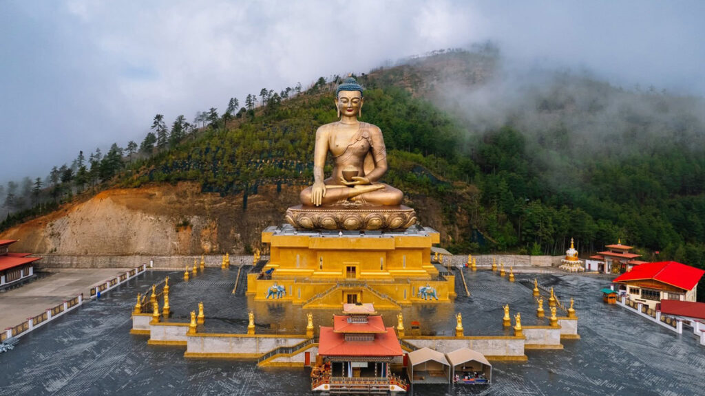 Buddha Dordenma statue in Thimphu, Bhutan, surrounded by misty forested hills.
