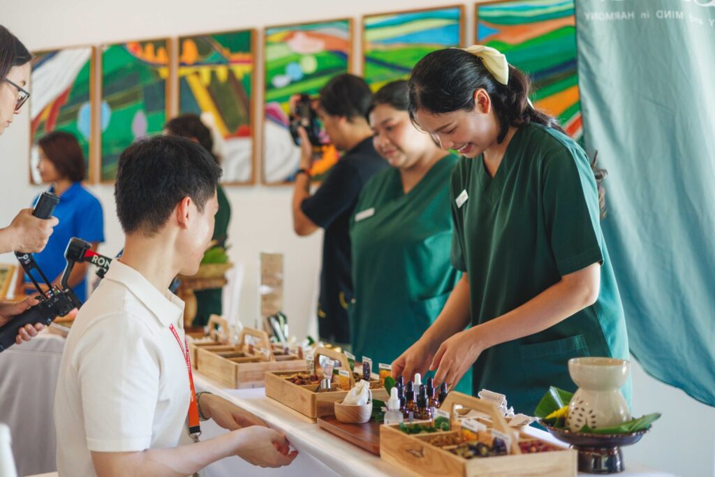 Wellness staff guide participants through Thai herbal activities during a coastal wellness programme.